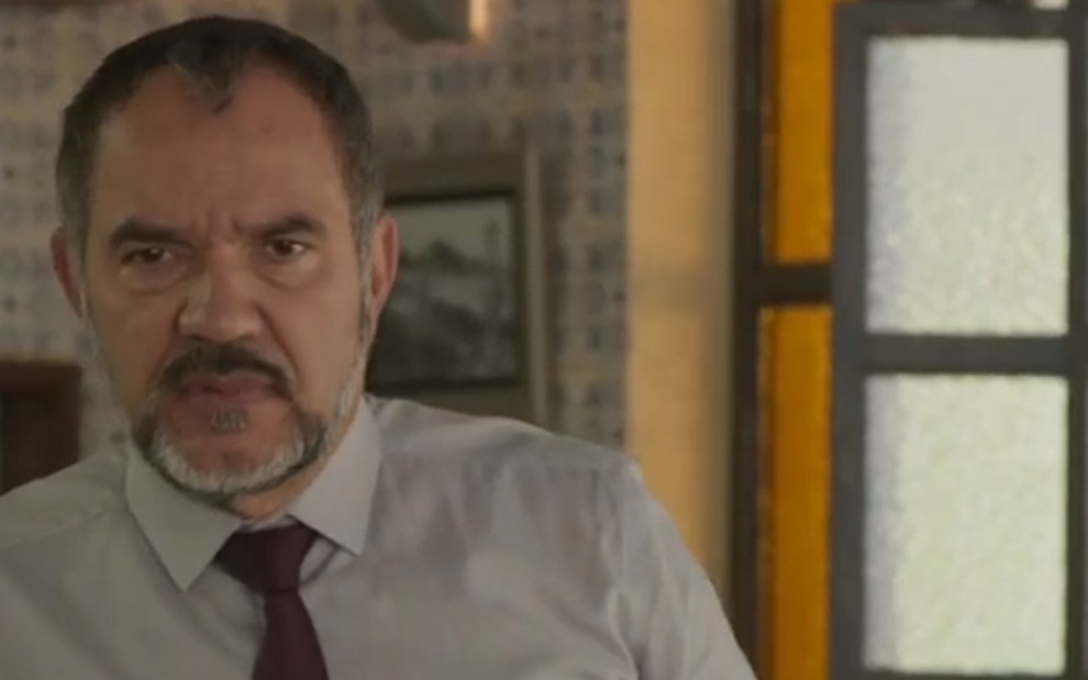 O ator Humberto Martins usa camisa e gravata e tem expressão preocupada em cena como Germano em Totalmente Demais