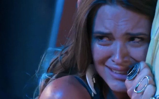 A atriz Juliana Paiva com cara de choro, abraçada a um homem, caracterizada como Cassandra em cena de Totalmente Demais