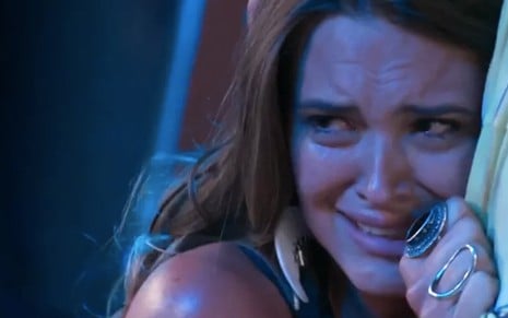 A atriz Juliana Paiva com cara de choro, abraçada a um homem, caracterizada como Cassandra em cena de Totalmente Demais