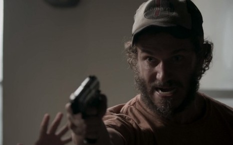 Paulo Rocha, que interpreta Dino na novela Totalmente Demais, com uma arma na mão