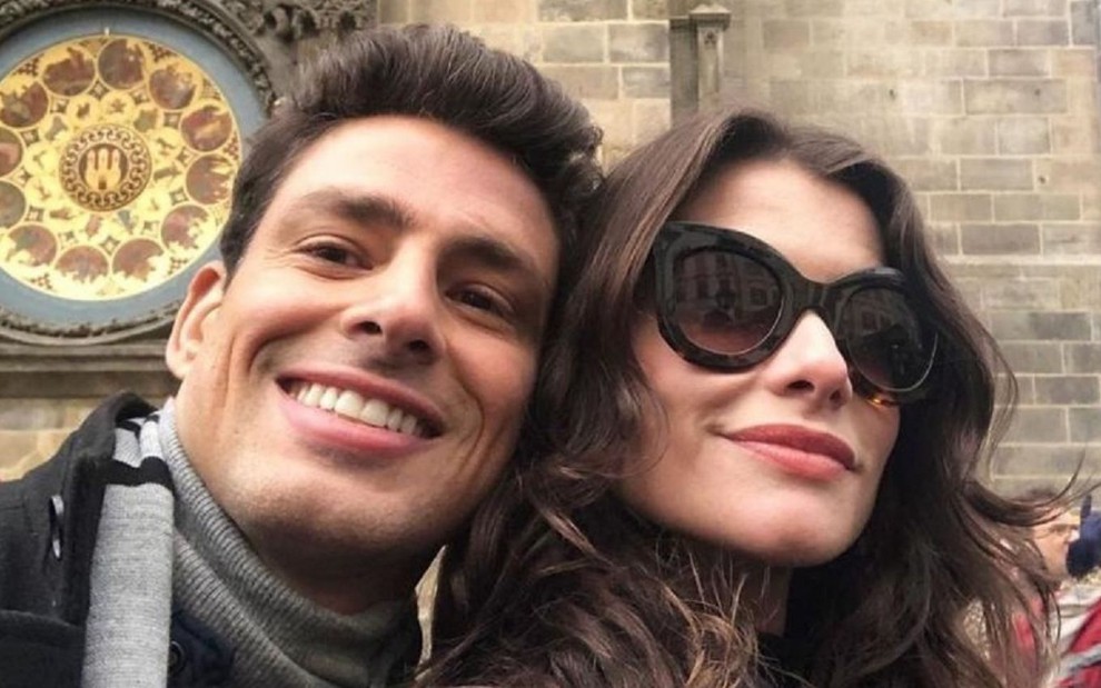 Os atores Cauã Reymond e Alinne Moraes sorriem abraçados em Praga, como personagens da novela Um Lugar ao Sol, da Globo