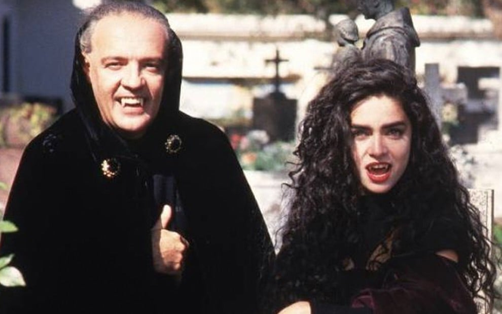 O ator Ney Latorraca à esquerda como Vlad e Claudia Ohana à direita como Natasha em um cemitério em cena de Vamp