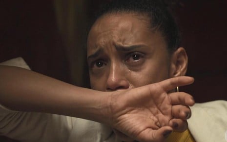 A atriz Taís Araujo coloca a mão na frente do rosto e chora em cena da novela Amor de Mãe, da TV Globo, em que interpreta Vitória
