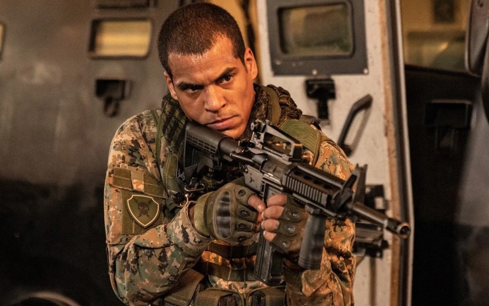O atro Marcelo Mello Jr segura uma arma e usa farda de policial do Bope em cena da série Arcanjo Renegado
