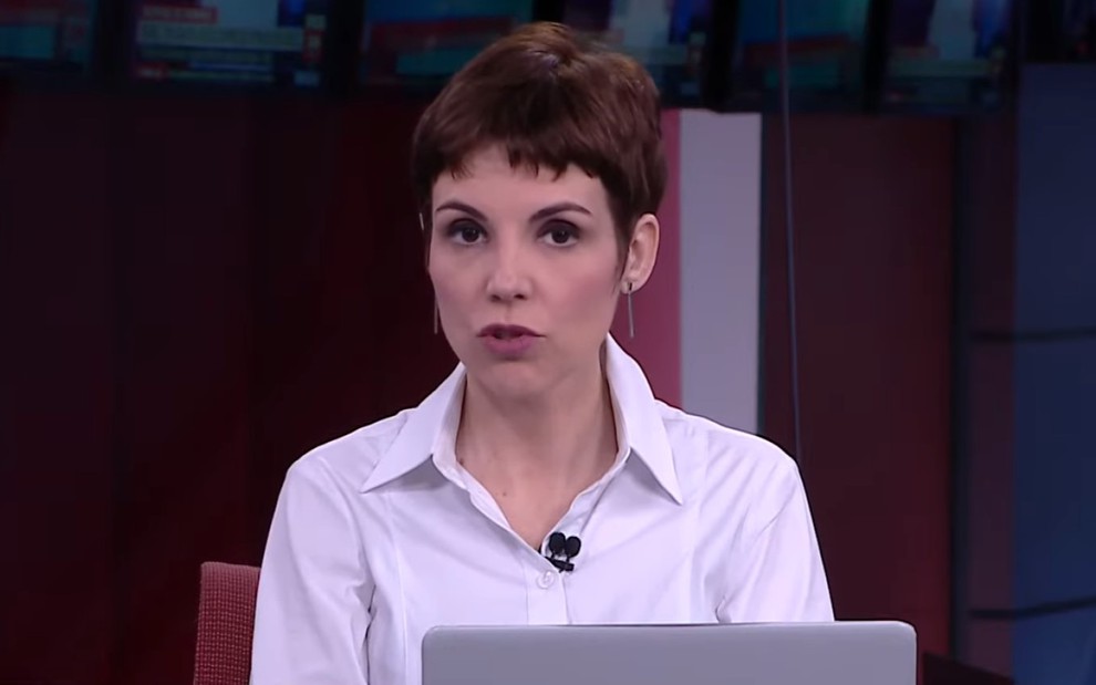 Gloria Vanique de camisa branca, apresentando um telejornal