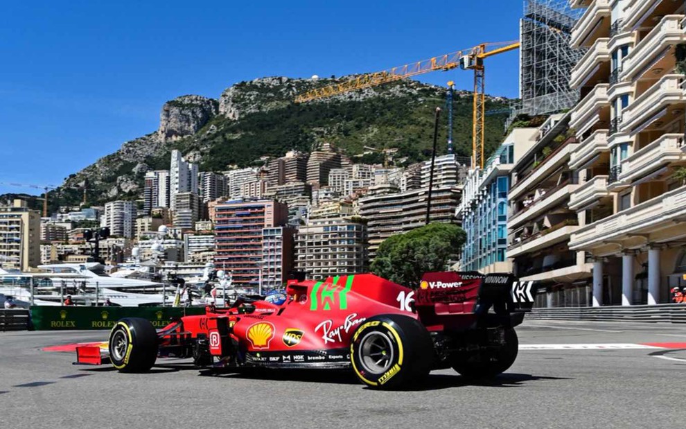 Carro vermelho de Fórmula 1 de Charles Leclerc da Ferrari na pista e cercado por detalhes da cidade de Mônaco