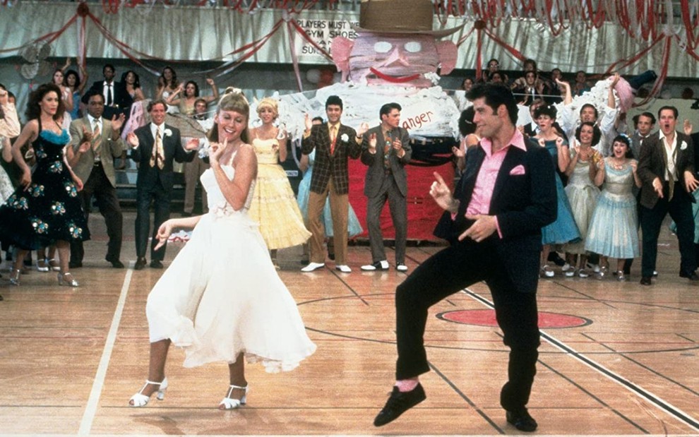 Olivia Newton-John e John Travolta dançam junto com colegas em cena de Grease - Nos Tempos da Brilhantina (1978)grease