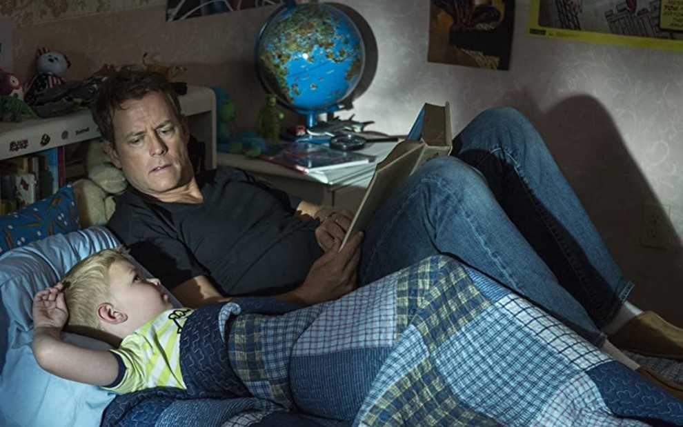 Deitados na cama, Greg Kinnear lê para o pequeno Connor Corum em cena do filme O Céu É de Verdade (2014)