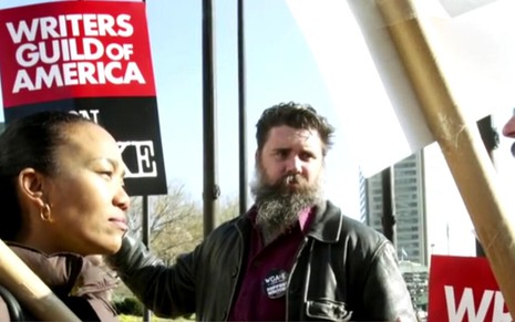 Mulher conversa com um homem branco barbudo, observado por outro rapaz, durante greve dos roteiristas de 2007