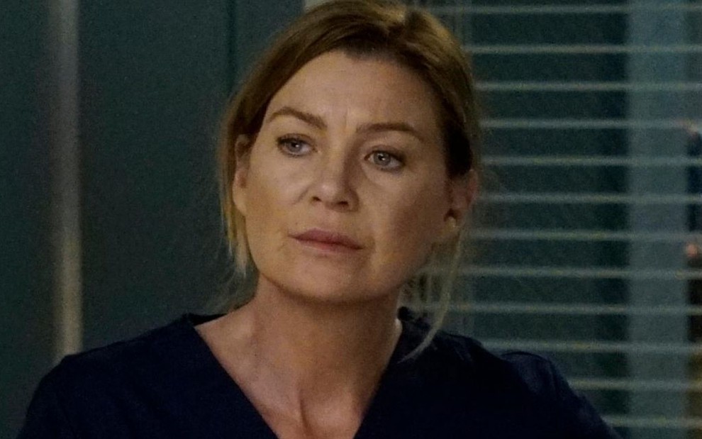 Com uma uniforme azul marinho de médica, Ellen Pompeo fica pensativa em cena da 16ª temporada de Grey's Anatomy