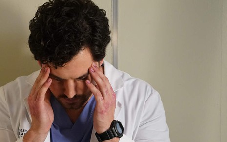 Com ambas mãos feridas, um cabisbaixo ator Giacomo Gianniotti passa os dedos na testa em Grey's Anatomy
