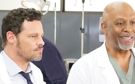Justin Chambers fecha a cara enquanto James Pickens Jr. sorri em cena da 16ª temporada de Grey's Anatomy