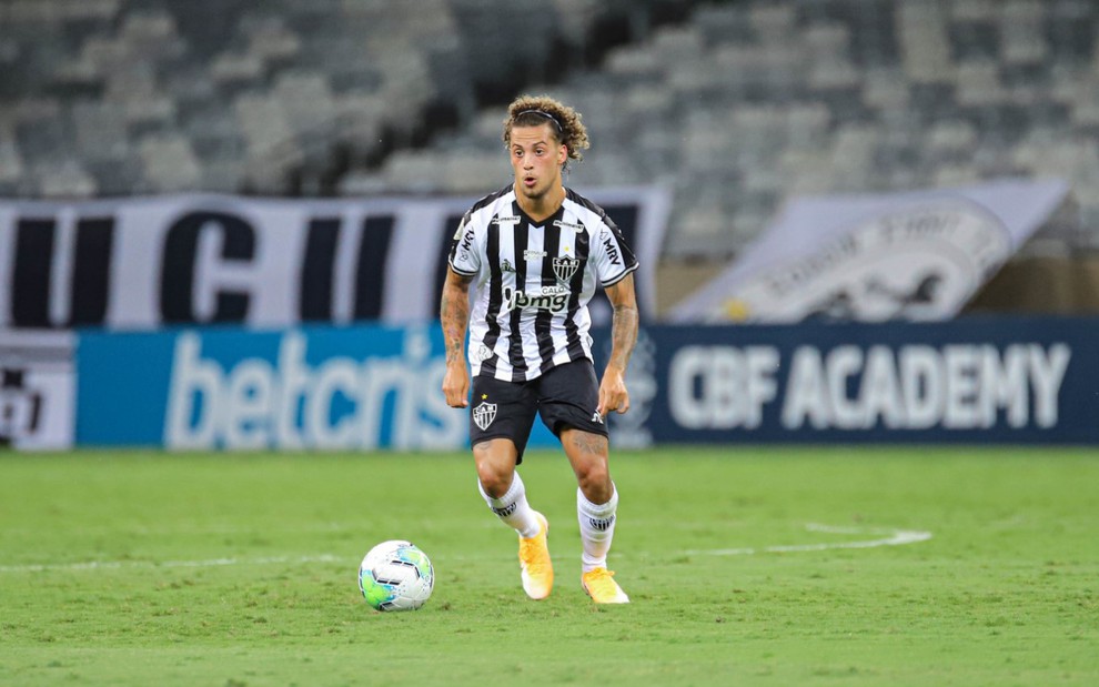 O lateral-direito Guga em campo, em lance com a bola próxima dos pés, vestido com uniforme do Atlético-MG nas cores preta e branca