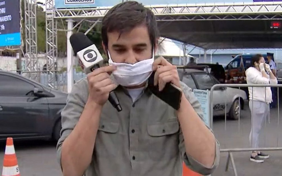 O repórter Guilherme Pimentel recoloca máscara durante reportagem ao vivo no SP1, na Globo, em 23 de maio de 2020