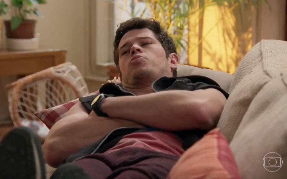 O ator José Loreto com expressão emburrada, deitado em sofá em cena de Haja Coração