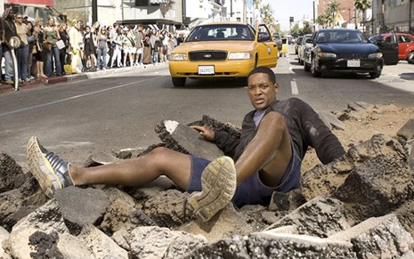 Will Smith caído em uma cratera no meio da rua em cena do filme Hancock