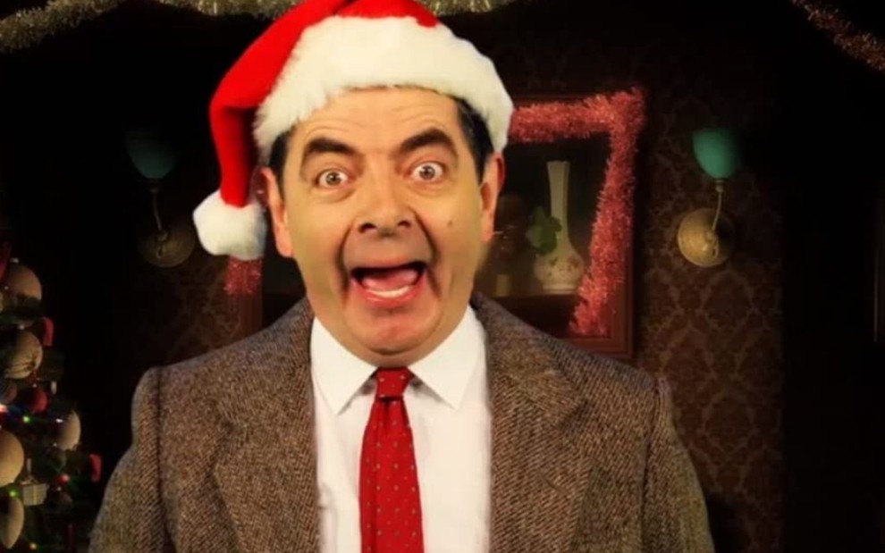 Rowan Atkinson com um chapéu de natal enquanto interpreta o personagen Mr. Bean