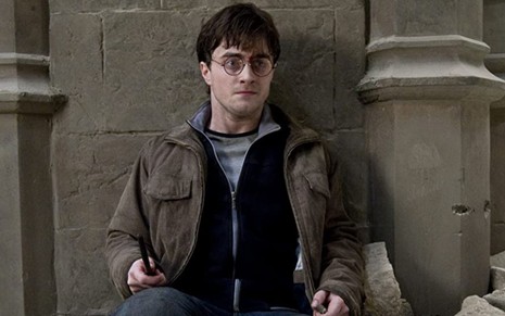 Daniel Radcliffe sentado com a varinha em punho em cena do filme Harry Potter e as Relíquias da Morte - Parte 2
