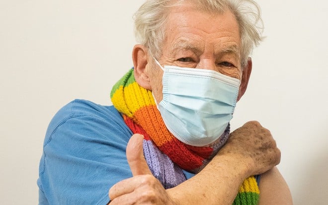 O ator Ian McKellen usando máscara após receber a vacina contra a Covid-19 faz sinal de positivo para a câmera