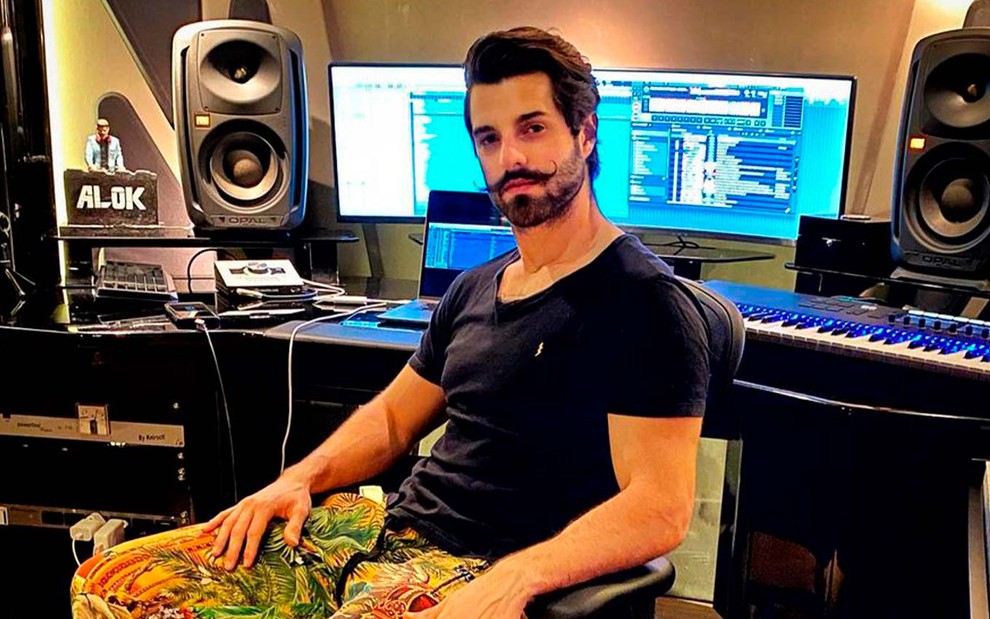Alok em foto publicada no Instagram: sentado, DJ está em um estúdio de música e olha para a câmera
