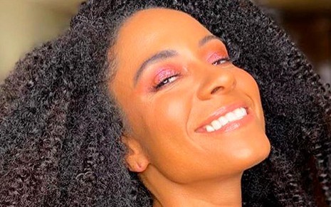 Cinnara Leal sorri, com sombra rosa nos olhos, em foto publicada no Instagram
