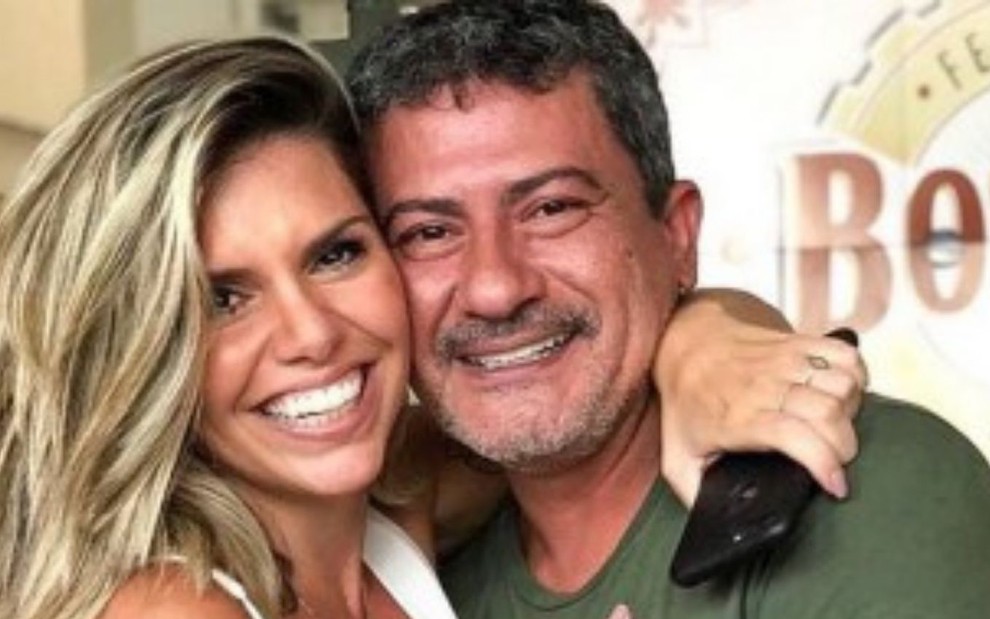 Cybelle Hermínio da Costa, loira, sorridente, abraçada a Tom Veiga, de camiseta verde