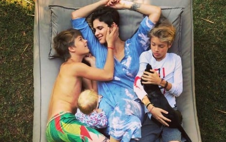 Foto da atriz deitada em uma rede com os filhos Maria, Francisco e João
