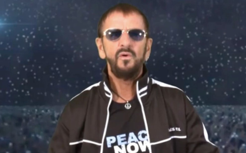 O bateirista e ex-integrante dos Beatles Ringo Starr em vídeo publicado no Instagram; ele aparece sério, de óculos escuros, camista e jaquetas pretas em um fundo de show virtual