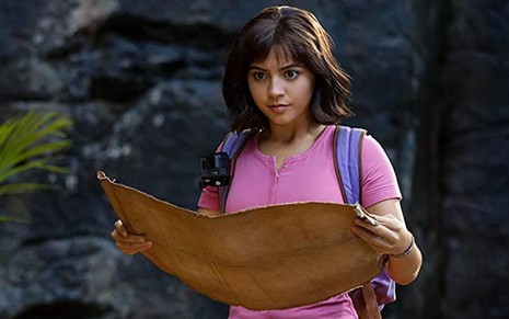 A atriz Isabella Merced caracterizada como a protagonista de Dora e a Cidade Perdida (2019); ela segura nas mãos um mapa