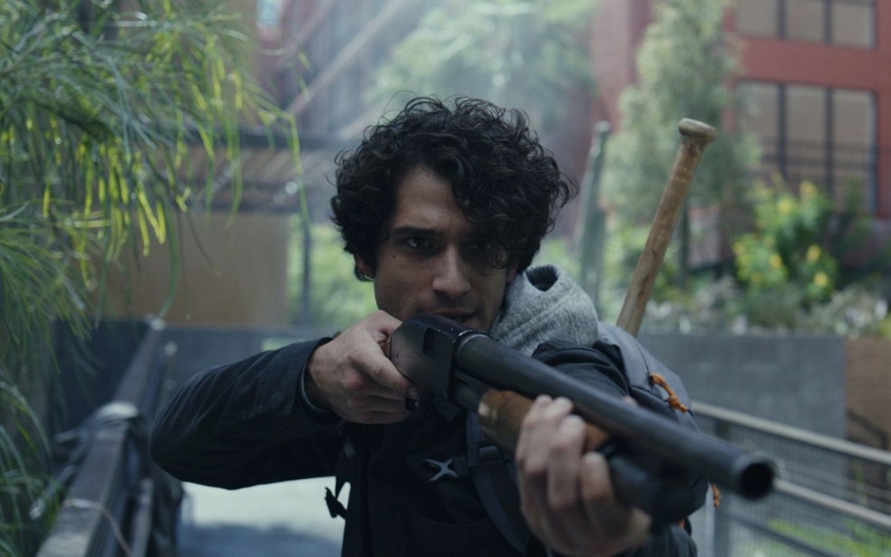 Tyler Posey aponta uma arma para alguém em cena do filme Isolado na Pandemia