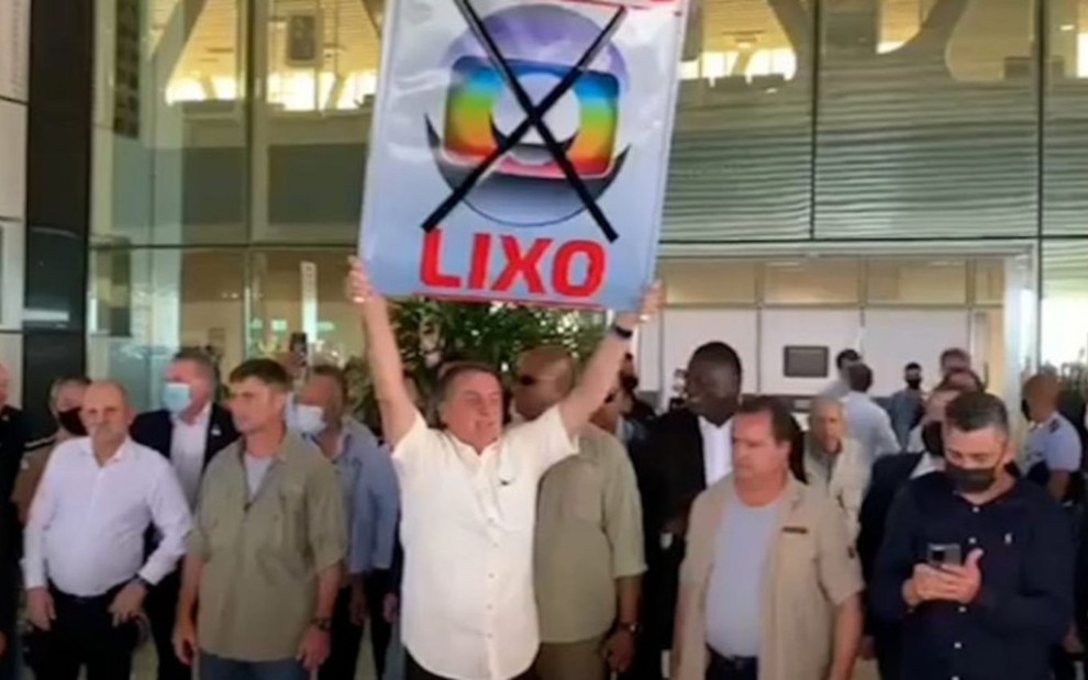 Imagem do presidente Jair Bolsonaro levantando o cartaz 'Globo Lixo' no aeroporto de Cascavel