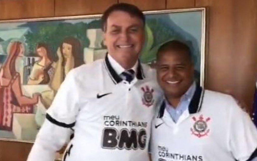 Imagem mostra o presidente Jair Bolsonaro e o ex-jogador Marcelinho Carioca com a camisa do Corinthians, abraçados