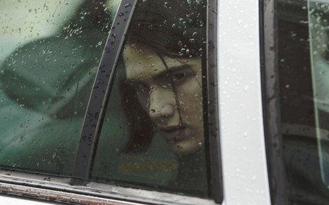 James Hamrick olhando pela janela de um carro, que está com gotas de chuva