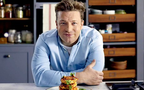 O chef britânico Jamie Oliver na cozinha, com expressão sorridente