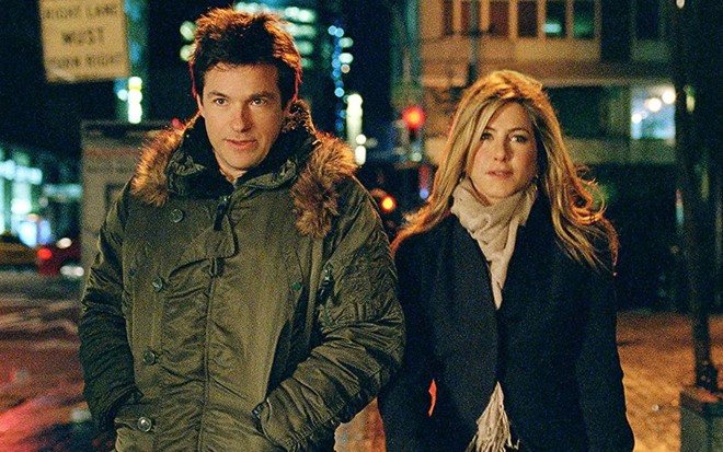 Com roupas de inverno, Jason Bateman e Jennifer Aniston caminham na rua em cena de Coincidências do Amor (2010)