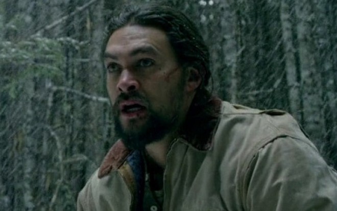 Jason Momoa com expressão de choque e medo em cena do filme Braven - Perigo na Montanha