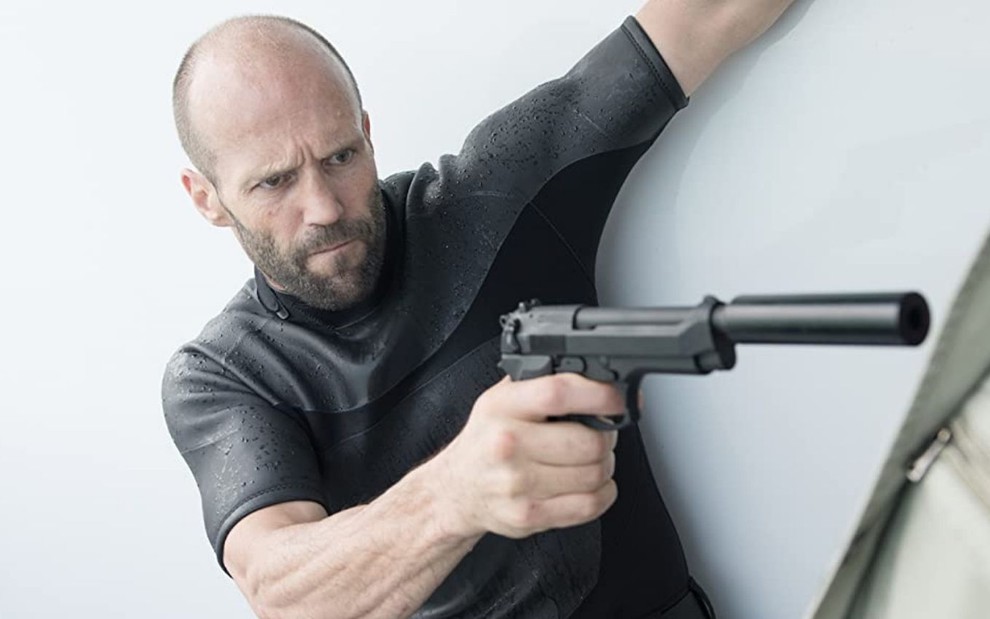 Jason Statham aponta uma arma para o lado em cena do filme Assassino a Preço Fixo 2 - A Ressurreição