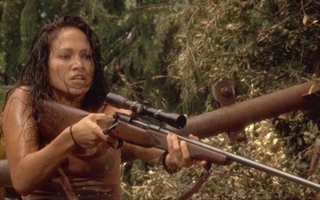 Jennifer Lopez como Terri Flores segurando arma em cena do filme Anaconda