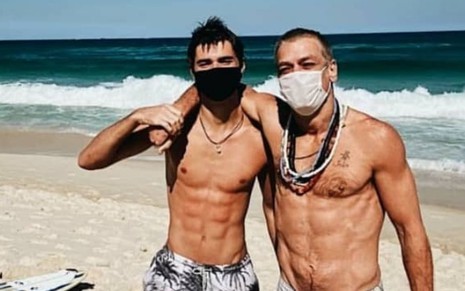 De máscara, João e Fabio Assunção se abraçam em foto na praia
