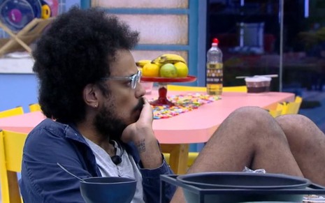 João Luiz Pedrosa reflexivo enquanto está sentado na cozinha do BBB21