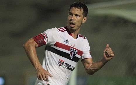 Hernanes com a camisa do São Paulo branca e com detalhes em preto e vermelho na horizontal correndo para a direita e olhando para a esquerda