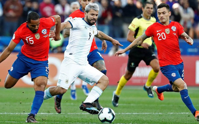 Jogador da Argentina com a bola dominada com dois jogadores do Chile ao seu redor em marcação