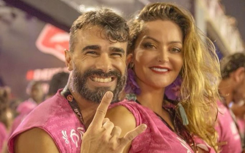 Jorge Sousa e Laura Keller de abadás roxo no carnaval; ambos sorrindo e posando para a foto