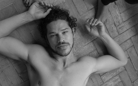 José Loreto sem camisa, deitado no chão, na foto em preto e branco