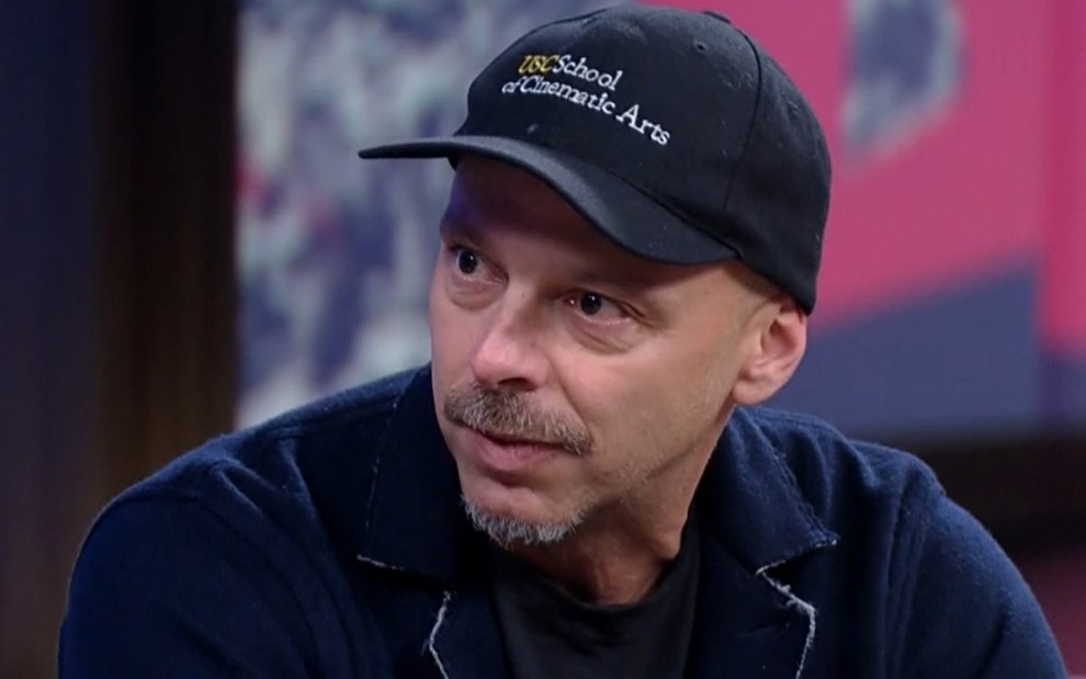 O cineasta José Padilha usa camiseta e boné preto durante entrevista no Conversa com Bial