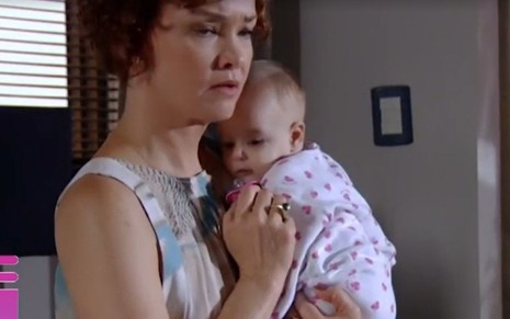 A atriz Julia Lemmertz, com um bebê no colo e expressão preocupada, em cena como Esther, na novela Fina Estampa
