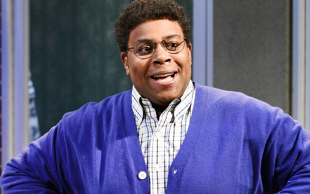 Kenan Thompson de blusa roxa e óculos de grau no humorístico Saturday Night Live