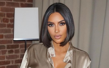 Kim Kardashian, morena, de cabelo chanel e blusa de seda em tom terroso