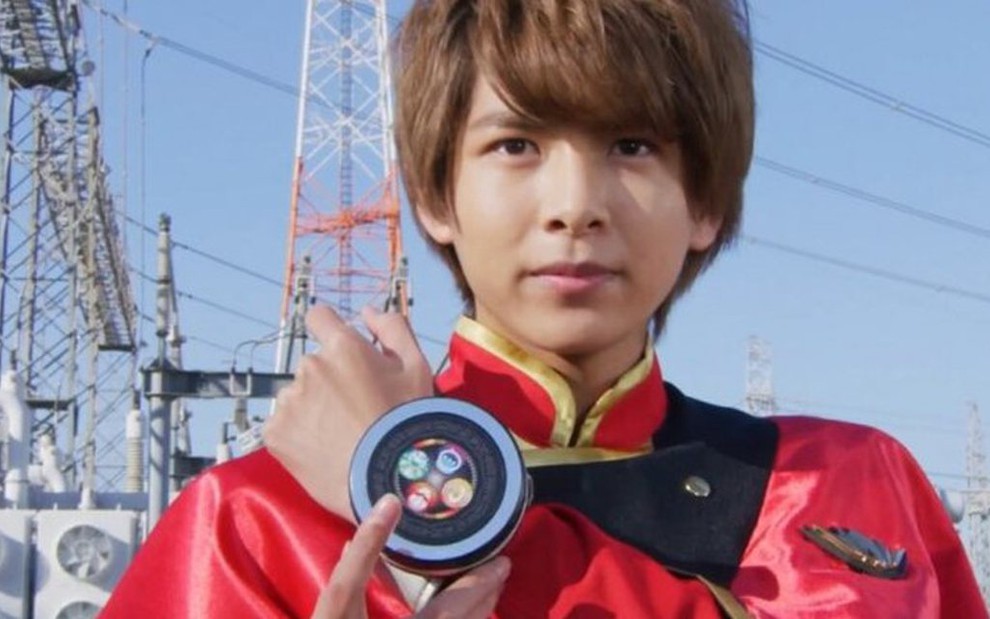 O ator Rio Komiya segura seu morfador em cena da série japonesa Mashin Sentai Kiramager
