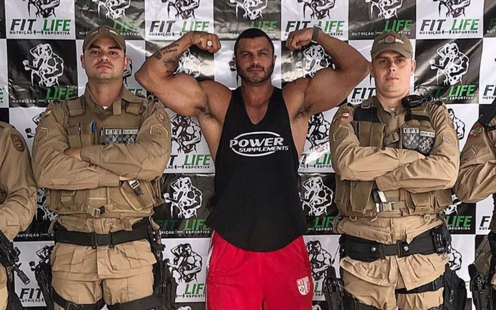 O campeão do primeiro Big Brother Brasil, Kleber Bambam, em foto posada com militares armados durante um evento promocional de marca de suplementos para o corpo em novembro deste ano